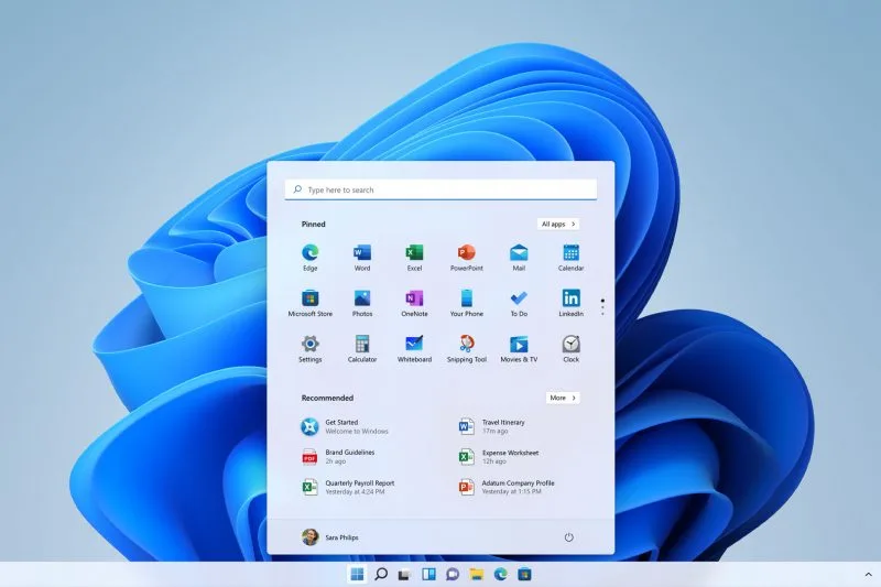 Un bureau Windows 11 Home affiche le menu Démarrer, applis épinglées et fichiers recommandés sur fond bleu, barre des tâches en bas.
