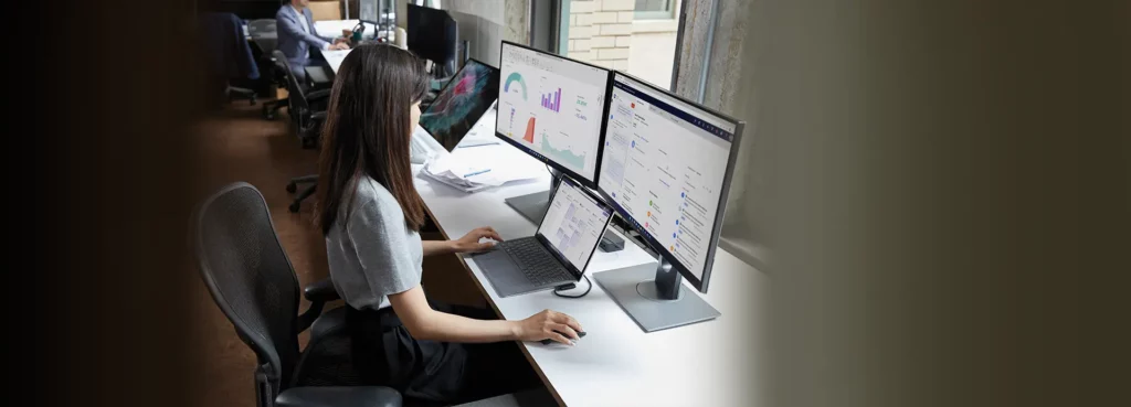 Utilisatrice professionnelle avec plusieurs écrans utilisant Microsoft 365 et Windows 11 Education pour l’analyse de données et la productivité