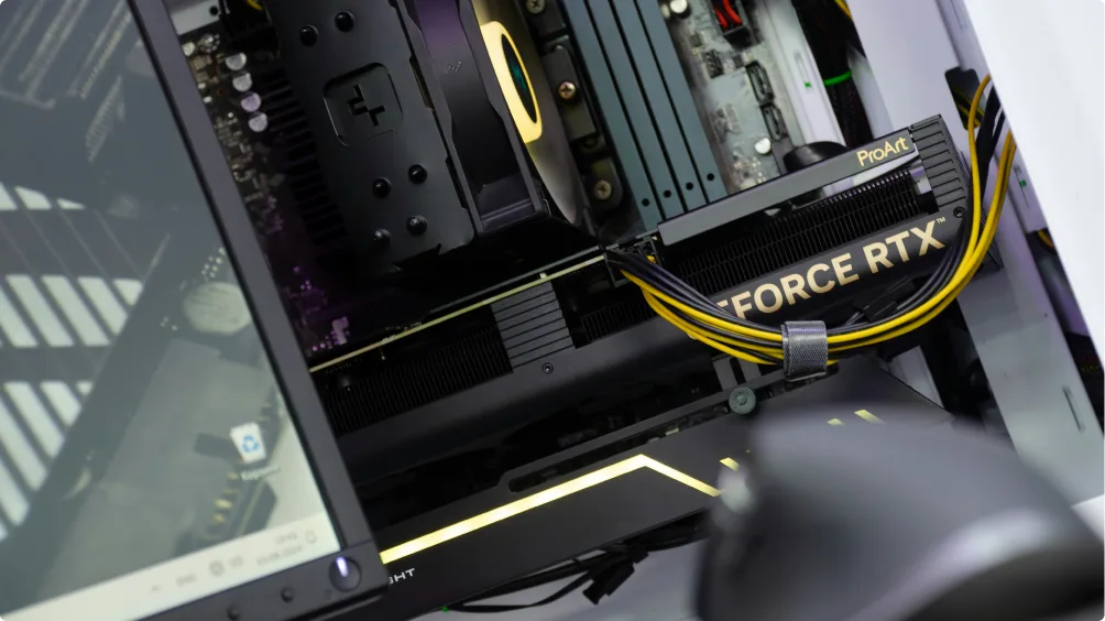 Vue rapprochée de l'intérieur d'un PC avec carte graphique GeForce RTX, câbles jaunes branchés, écran partiellement visible à côté.