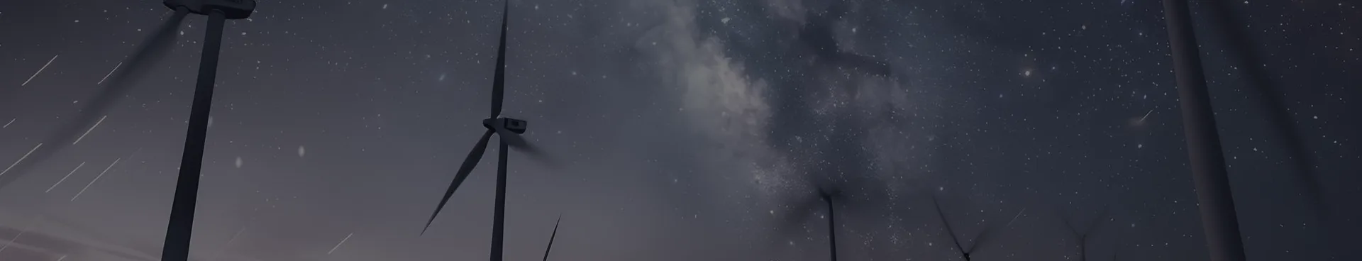 Des éoliennes se dressent sous un ciel nocturne étoilé et la Voie lactée, pales floues et traînées lumineuses d'étoiles en fond.
