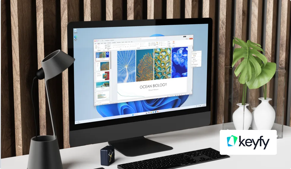 Bureau moderne avec grand écran sur une présentation de biologie marine, lampe, plante verte, clavier, souris et logo Keyfy en bas à droite.