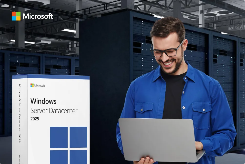 Un homme en bleu sourit dans une salle de serveurs avec un ordinateur portable, près d'une boîte Microsoft Windows Server 2025.