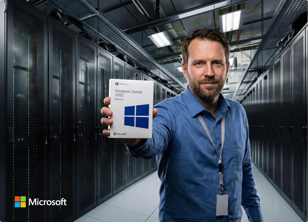 Un homme en chemise bleue tient une boîte Windows Server 2022 Standard dans une salle serveurs avec racks noirs et logo Microsoft.