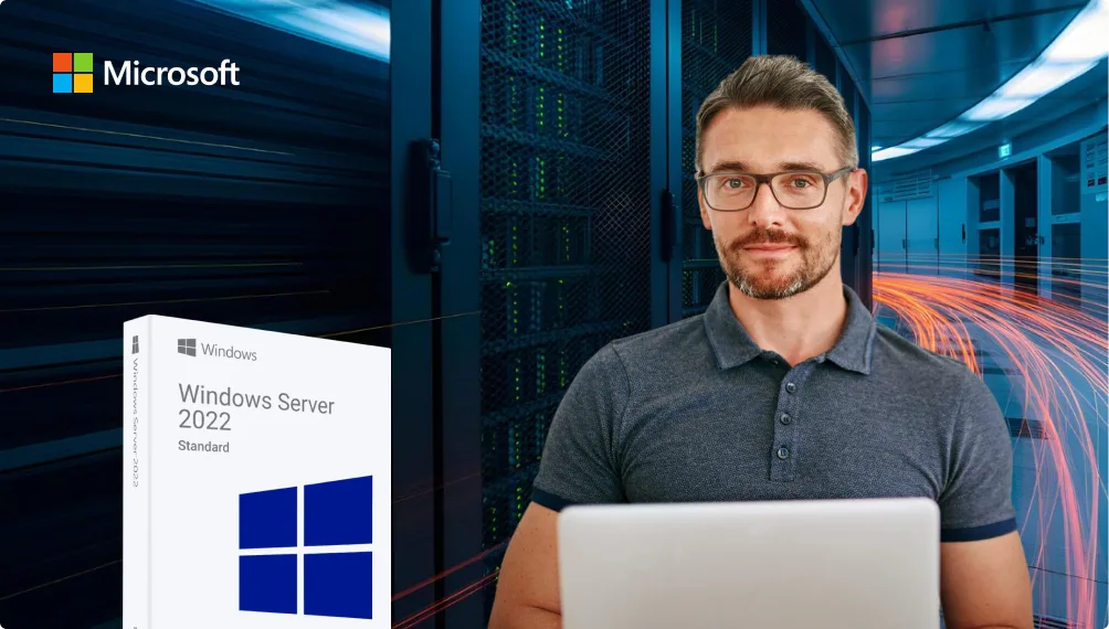 Un homme barbu avec des lunettes travaille sur un ordinateur portable, près d'une boîte Windows Server 2022 Standard. Racks serveurs et logo Microsoft en arrière-plan.
