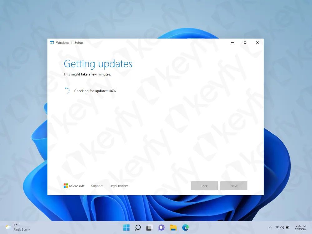 Une fenêtre de configuration de Windows 11 est affichée sur un écran de bureau, montrant l'obtention des mises à jour avec une barre de progression à 46 %. L'arrière-plan a un motif abstrait bleu et la barre des tâches est visible en bas.
